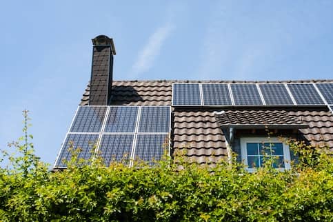 Home with brown roof, chimney, and solar panels.