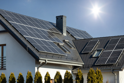 White home with black roof covered in solar panels.