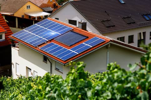 Solar panels installed on the red roof of a house.