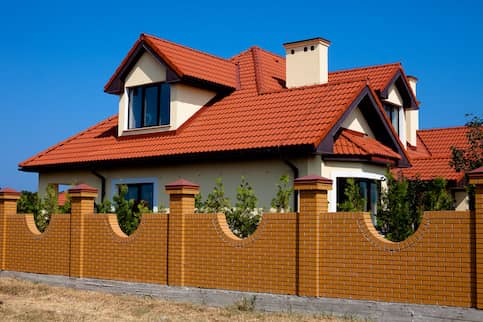 Spanish colonial style home with dormers and red roof.