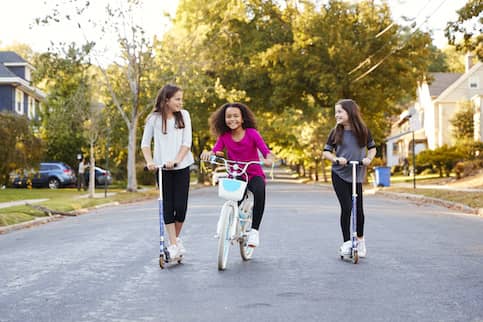 Three young girls playing on street.