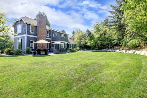 Blue two story house with big lawn.