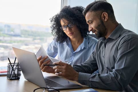 Two office workers analyzing paperwork.