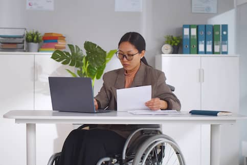 Asian-American woman in wheelchair doing paperwork.