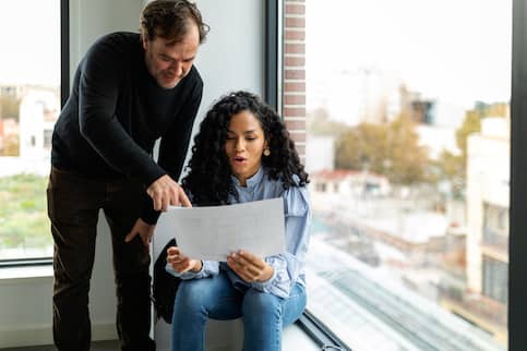 Woman Looking At Blueprints With Real Estate Agent