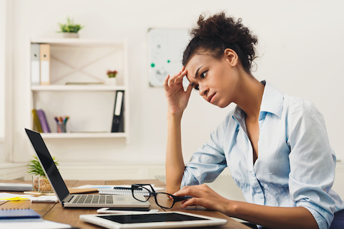 Young woman looking concerned at information on laptop.