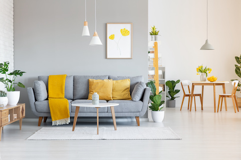 Contemporary styled living room with open concept kitchen in background and yellow accents.