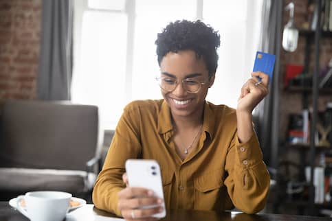 Young African-American woman uses credit card for online shopping.