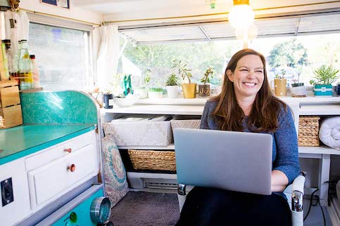 Women smiling with laptop in mobile tiny home.