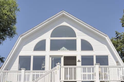 Converted white barn with plenty of windows and a balcony.