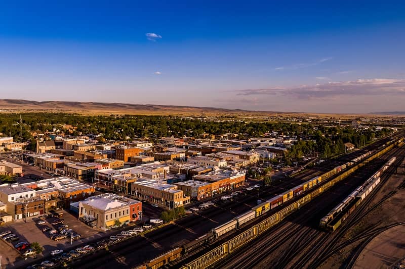 Aerial view of Laramie, with hills, trees, commercial buildings and trains.