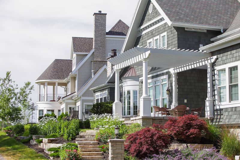 Row of coastal style cottages featuring bay windows, grey shingles and white washted trim..