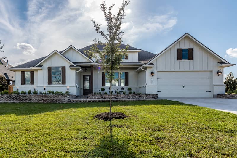 Modern farmhouse with tree in front.