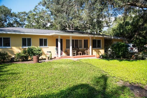 Single story Ranch style home with a large tree in the front yard.