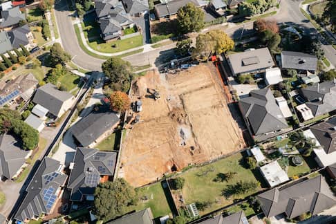 Aerial view of subdivision with empty plot of land situated between two homes.