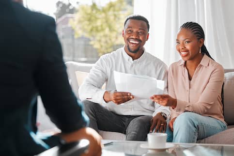 Broker and couple discussing a contract in a house in front of a wide window