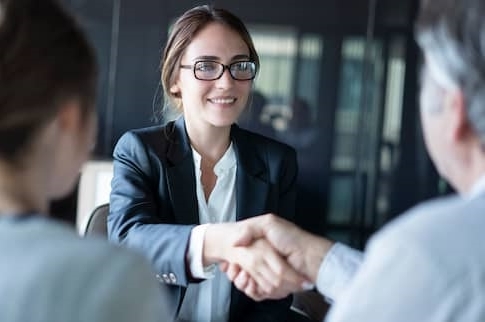 Businesswoman shaking hands with older couple.