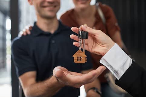 Close Up Of Real Estate Agent Giving Keys To Couple
