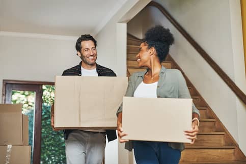 Smiling, happy and cheerful interracial couple carrying boxes 