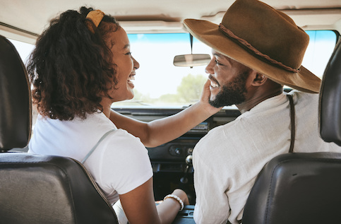 Happy couple in new car looking at one another and smiling.