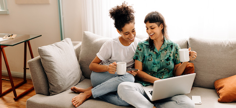 Lesbian couple on couch paying closing costs while having coffee.