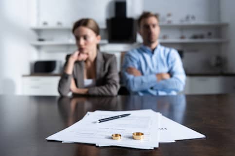 Couple with divorce contract and rings on brown table
