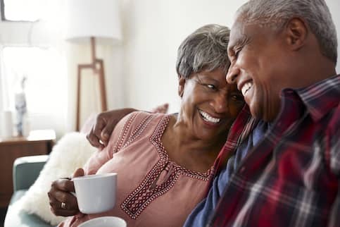 Older couple cuddling with coffee.