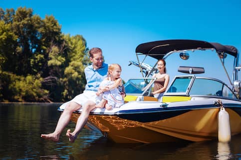 Mother, father and young daughter enjoying time on a blue and yellow motor boat on a lake.