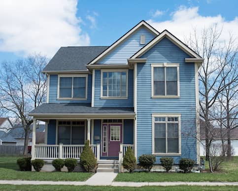 Two-story blue house with purple door and white front porch.