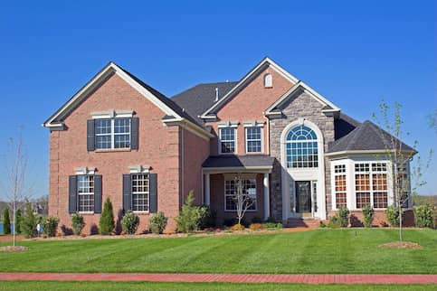 Large brick house against bright blue sky.