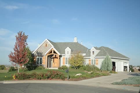 Grey craftsman style home with wood features and three car garage.