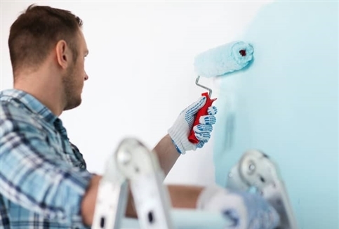 Man painting blue walls.