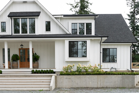 Modern farmhouse style home with white exterior and grey roof and large porch.