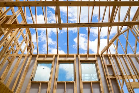 Wooden framing of a new constructed house under a blue sky.