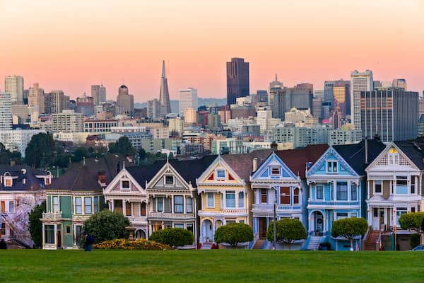 Row of historic colorful Victorian homes in San Francisco known as the Painted Ladies at sunset.