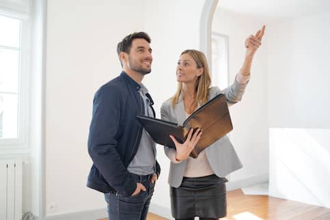 Female real estate agent pointing out features of contemporary home to potential buyer.