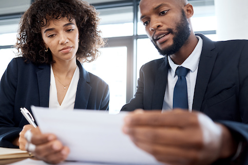 Woman and man reviewing real estate investments together, dressed in business attire..