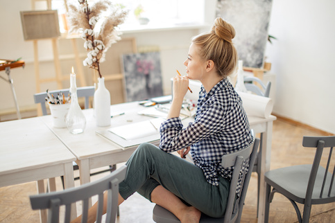 Young woman looking out window and thinking before drawing.