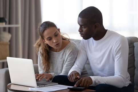 Young couple calculating bills on laptop.