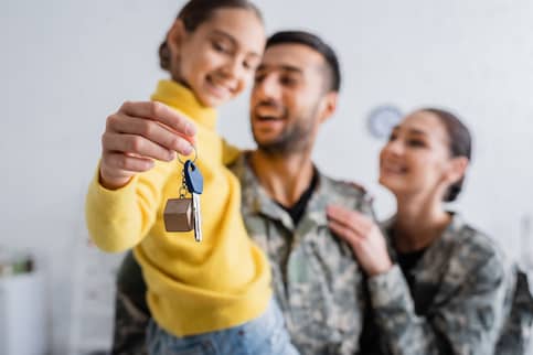 Blurred parents in military uniform holding daughter with key at home