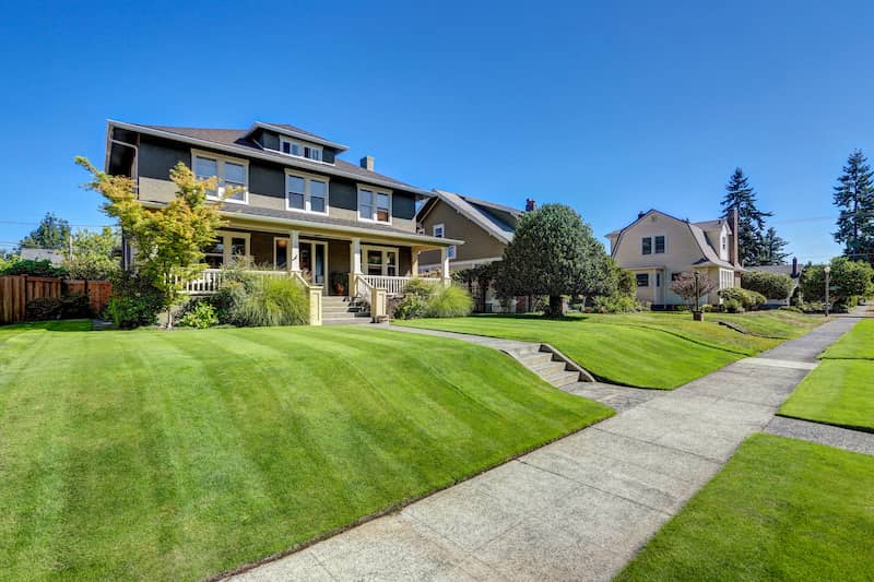 Green and beige craftsman style house with large, covered porch.