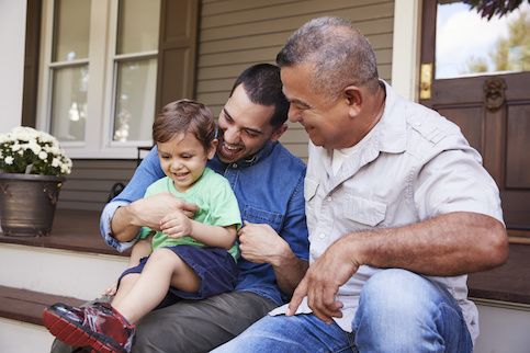 A father, son, and grandfather on porch steps outside home.