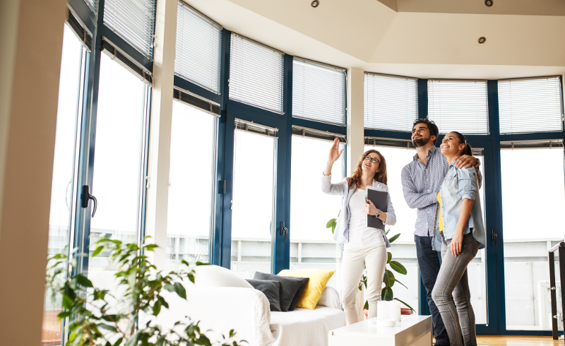 Couple with agent looking at home standing near windows.