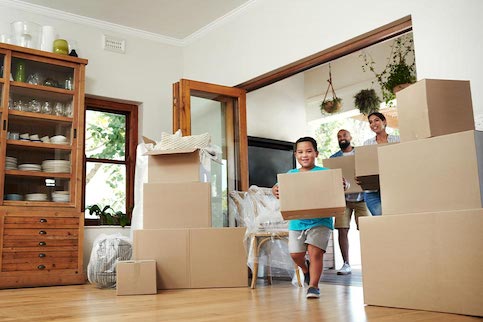 Family carrying boxes moving into their new home.