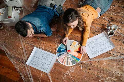 Woman and man laying on tarp browsing paint colors.