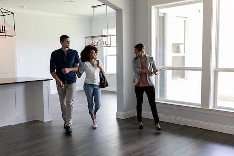 A couple walks through a home showing with their real estate agent.