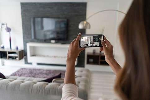 Woman taking photo of living room to sell home.