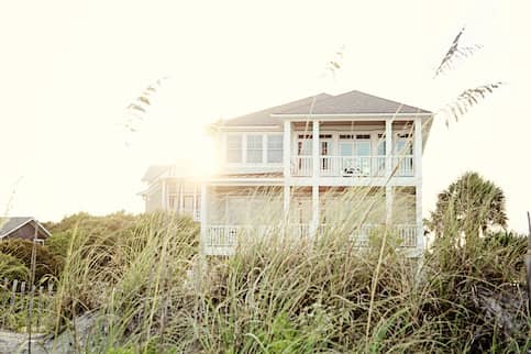 White beach house in tall grass.
