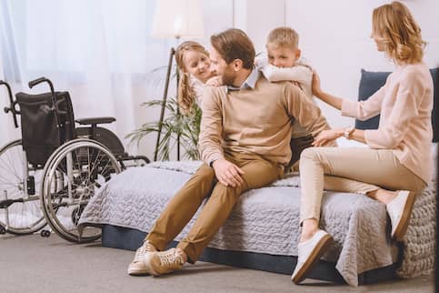 family smiling, sitting in lower, wheelchair-accessible bed