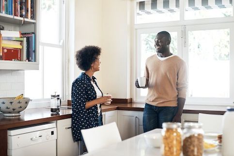 Young African American couple standing in their kitchen.